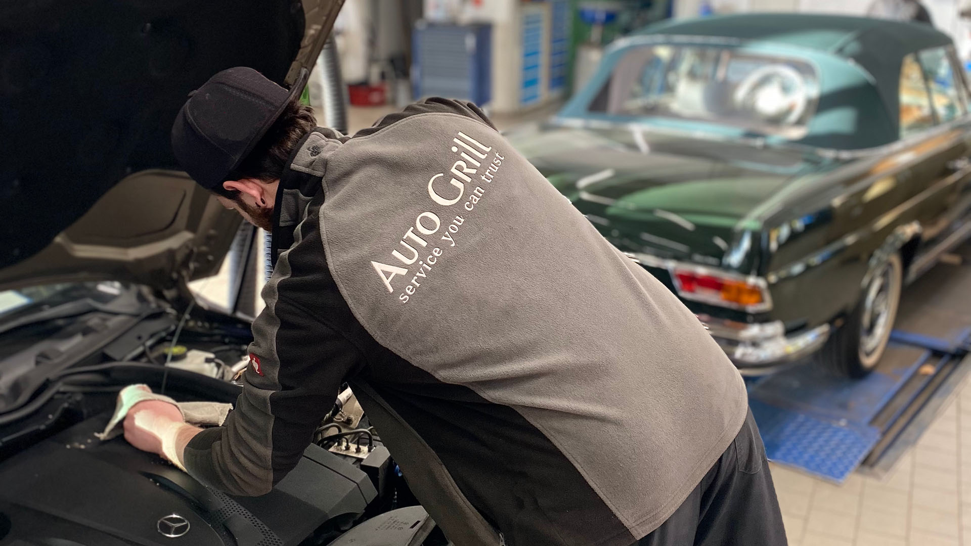 Ein Service-Mechatroniker führt einen Ölservice vor der geöffneten Motorhaube eines Mercedes-Benz durch