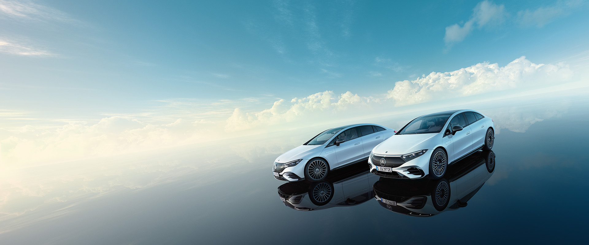 Mercedes-Benz EQE und EQS in einer surrealen Welt mit blauem Himmel und glänzend schwarzem Boden