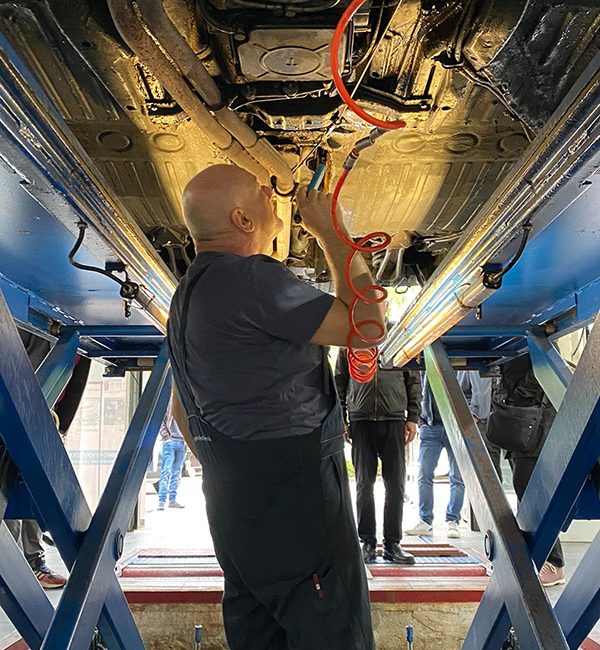 Mechatroniker arbeitet unter dem Auto auf der Hebebühne